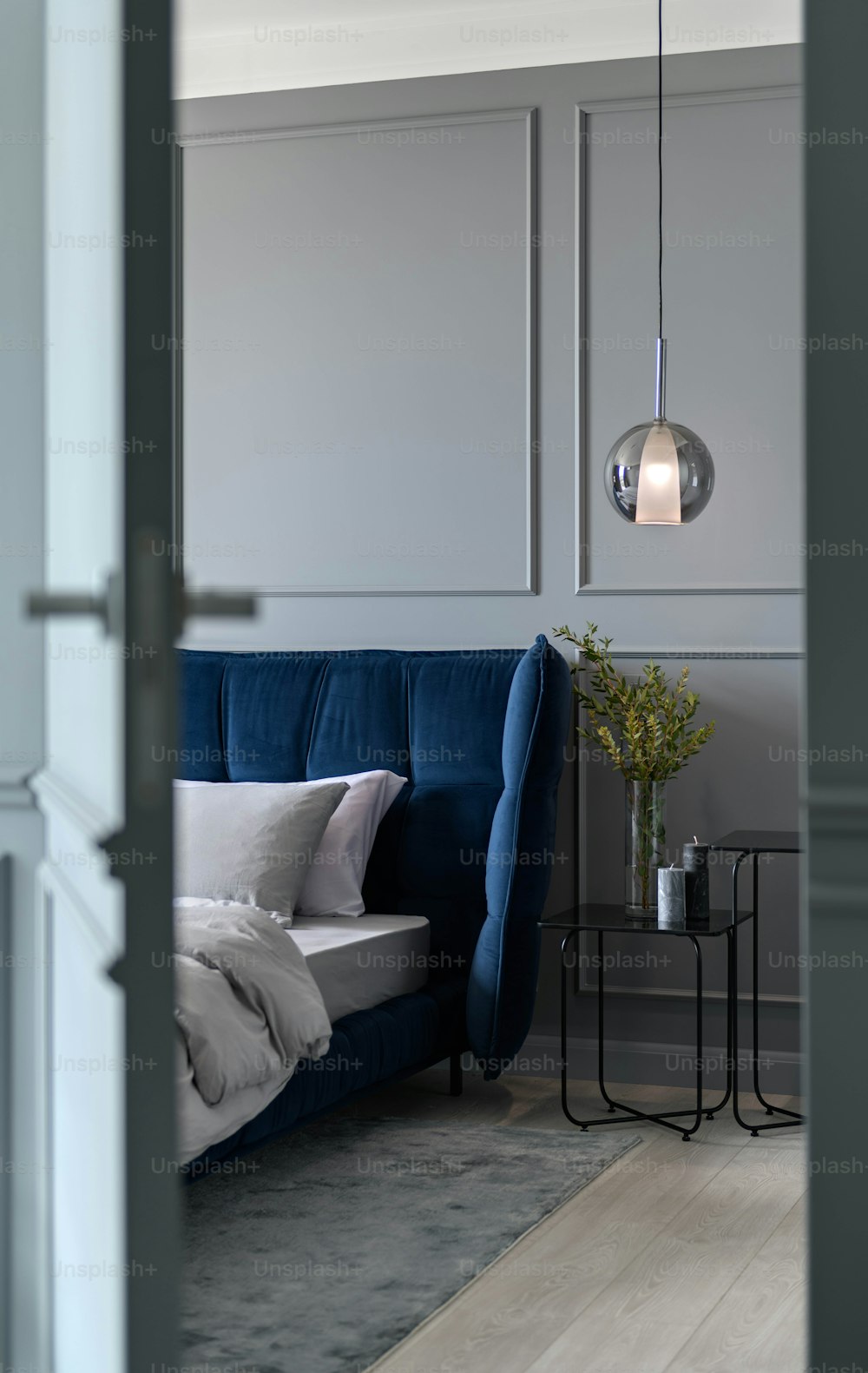 um sofá azul sentado em uma sala de estar ao lado de uma lâmpada