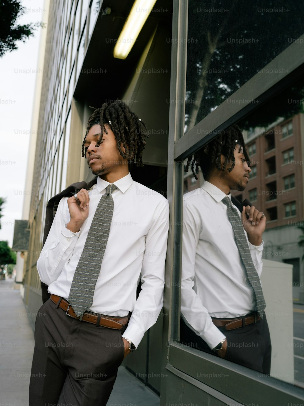 a man in a white shirt and tie standing in front of a window