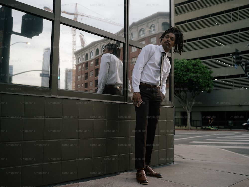 um homem em pé na frente de uma janela ao lado de um edifício