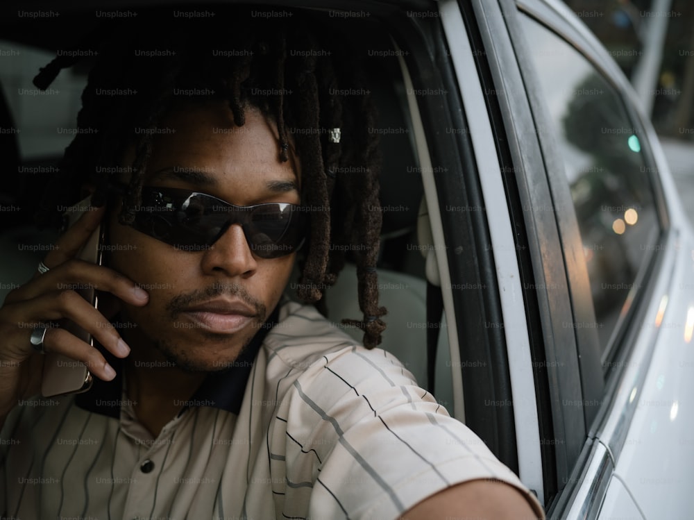 a man sitting in a car talking on a cell phone