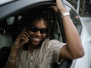 a man with dreadlocks sitting in a car talking on a cell phone