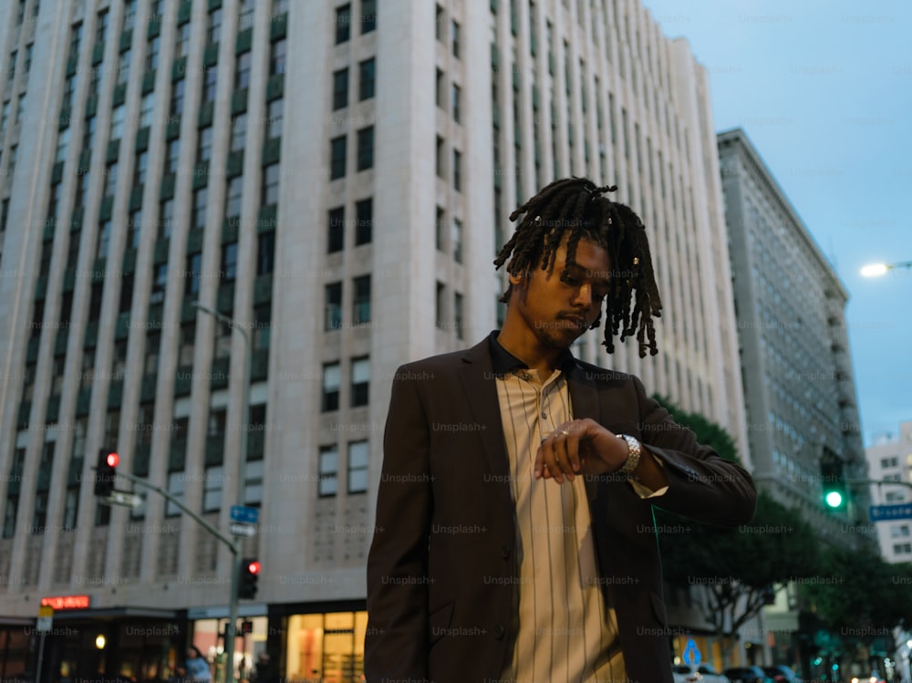 a man with dreadlocks standing in front of a tall building