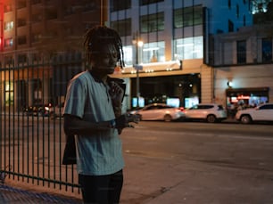 a man standing on a sidewalk next to a fence