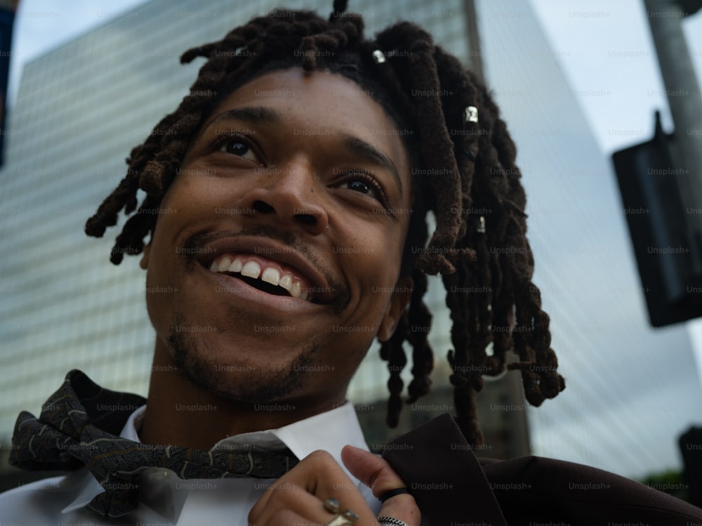 a man with dreadlocks and a white shirt is smiling