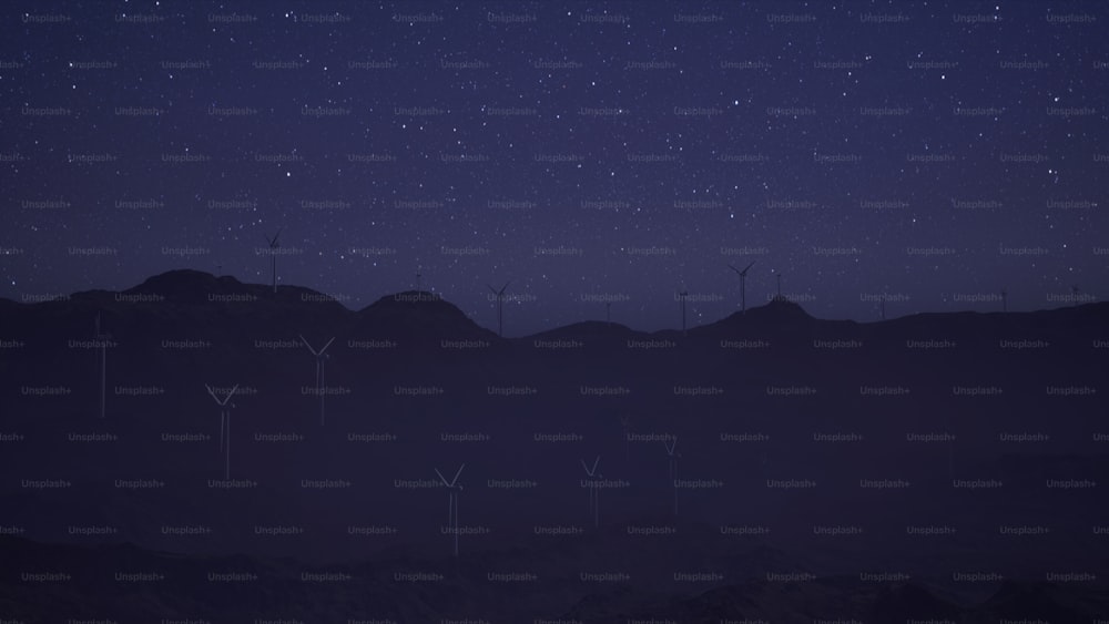 a group of windmills on a hill at night