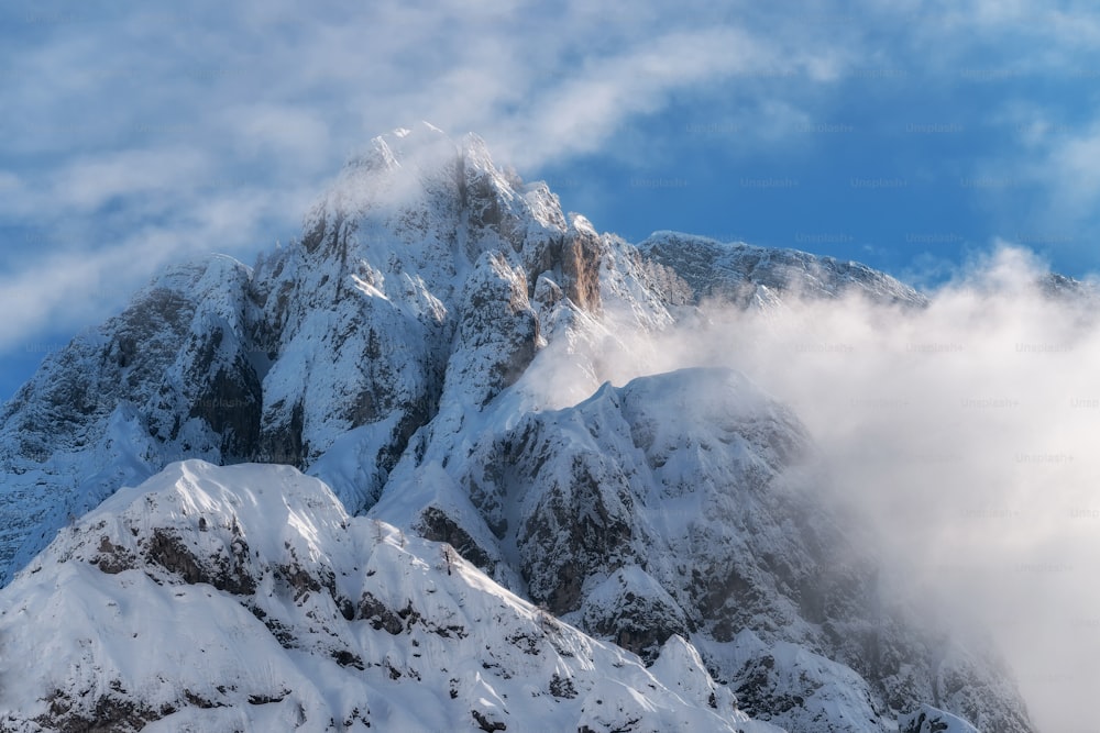 Una montaña cubierta de nieve y nubes bajo un cielo azul
