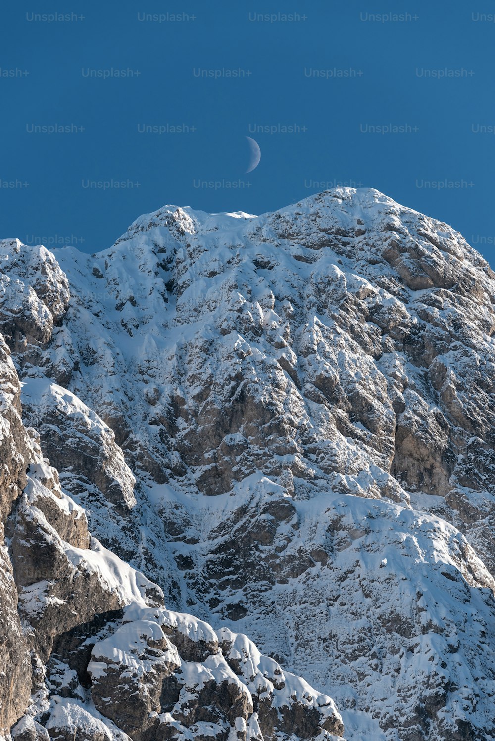 Una montaña nevada con media luna en el cielo