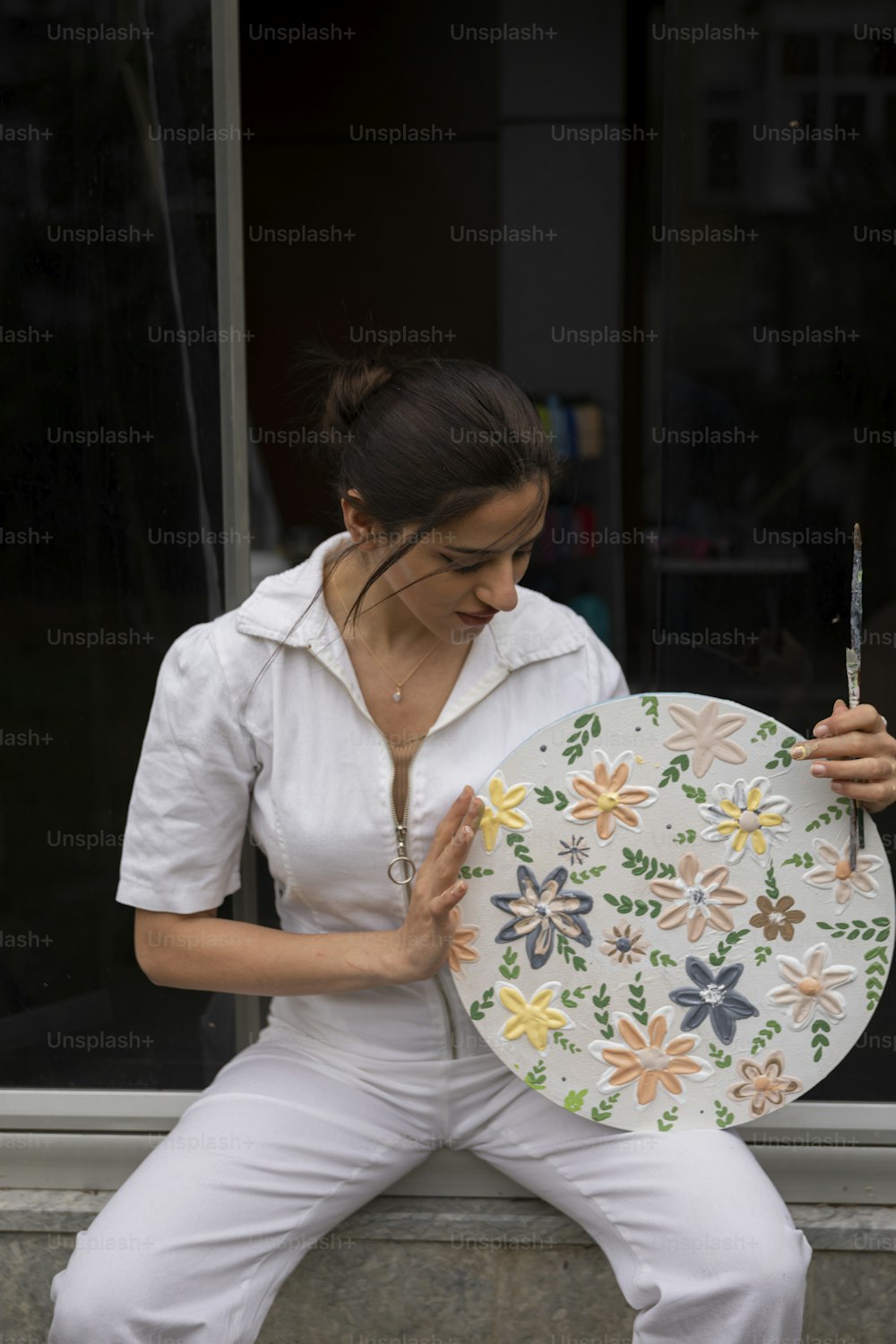 une femme assise sur un rebord tenant une assiette
