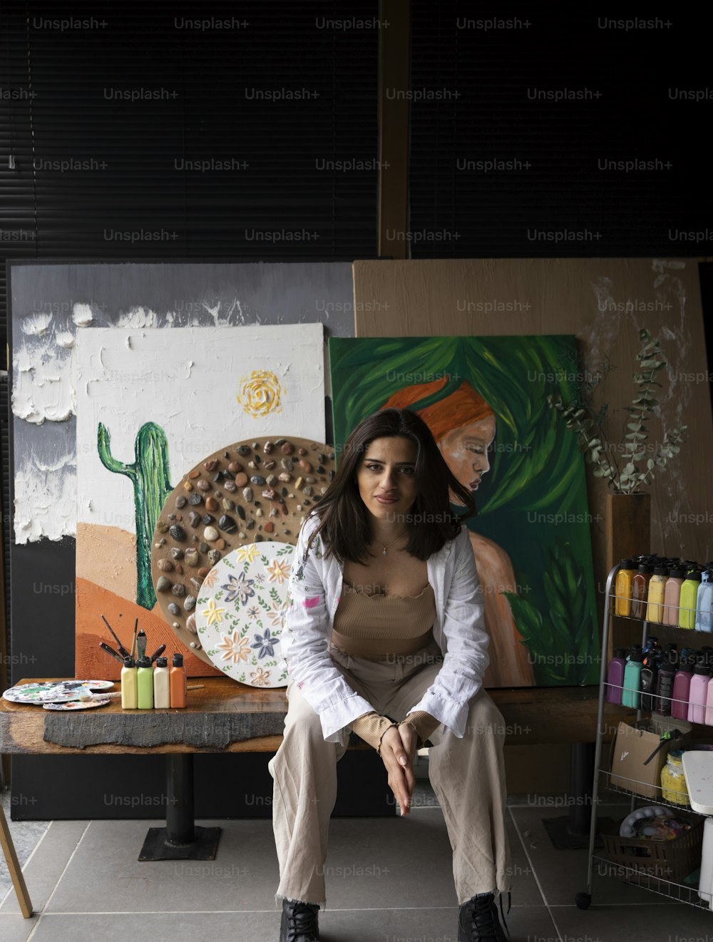 uma mulher sentada em um banco na frente de uma pintura