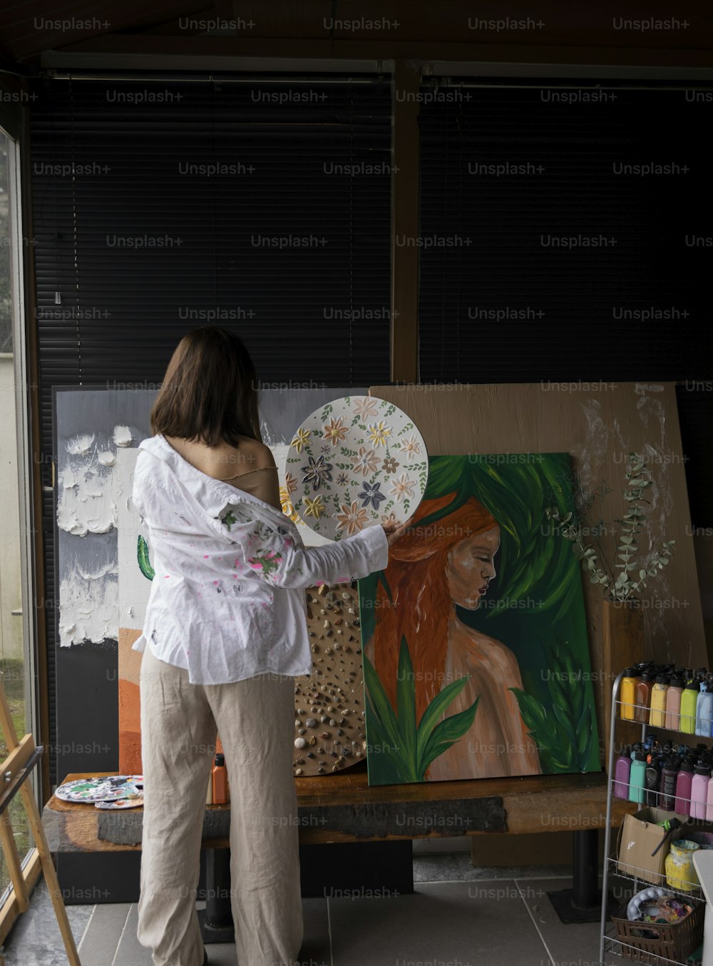a woman is painting a picture on a easel