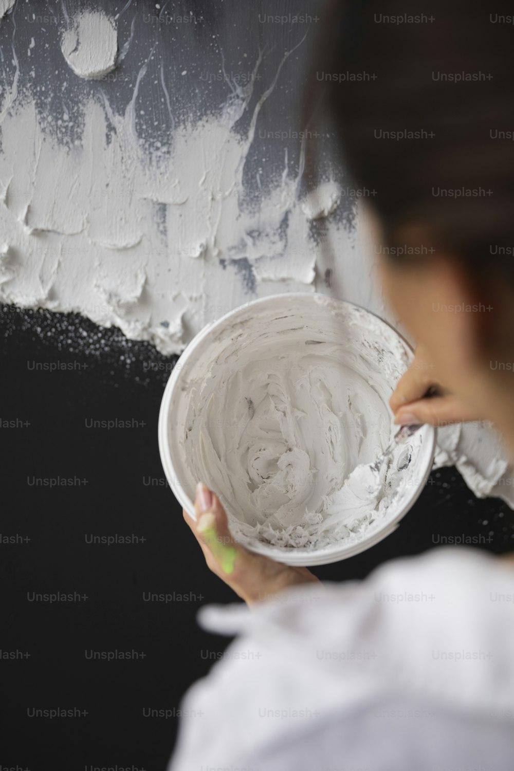 Une femme peint un mur avec de la peinture blanche