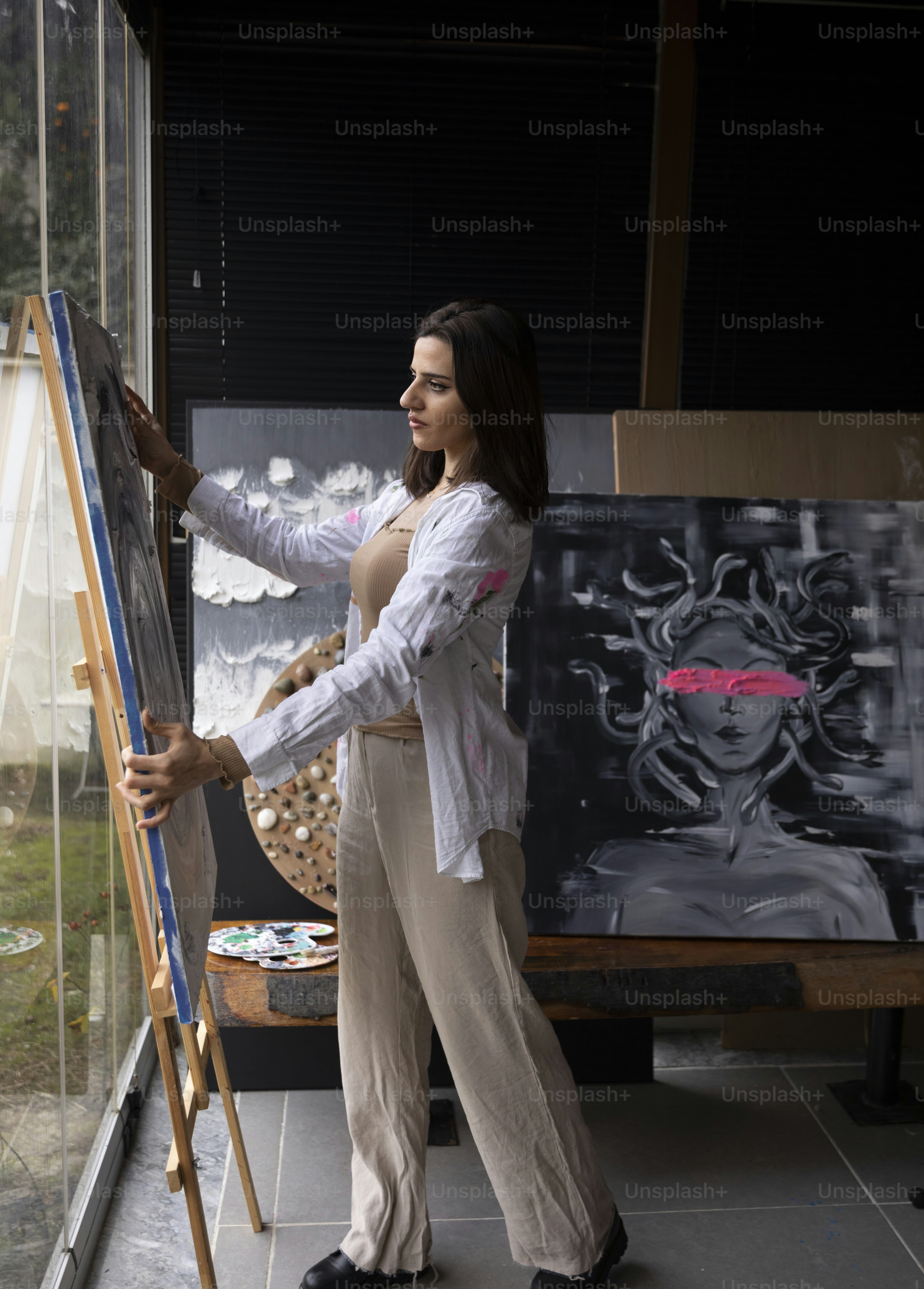 a woman standing in front of a painting on a easel
