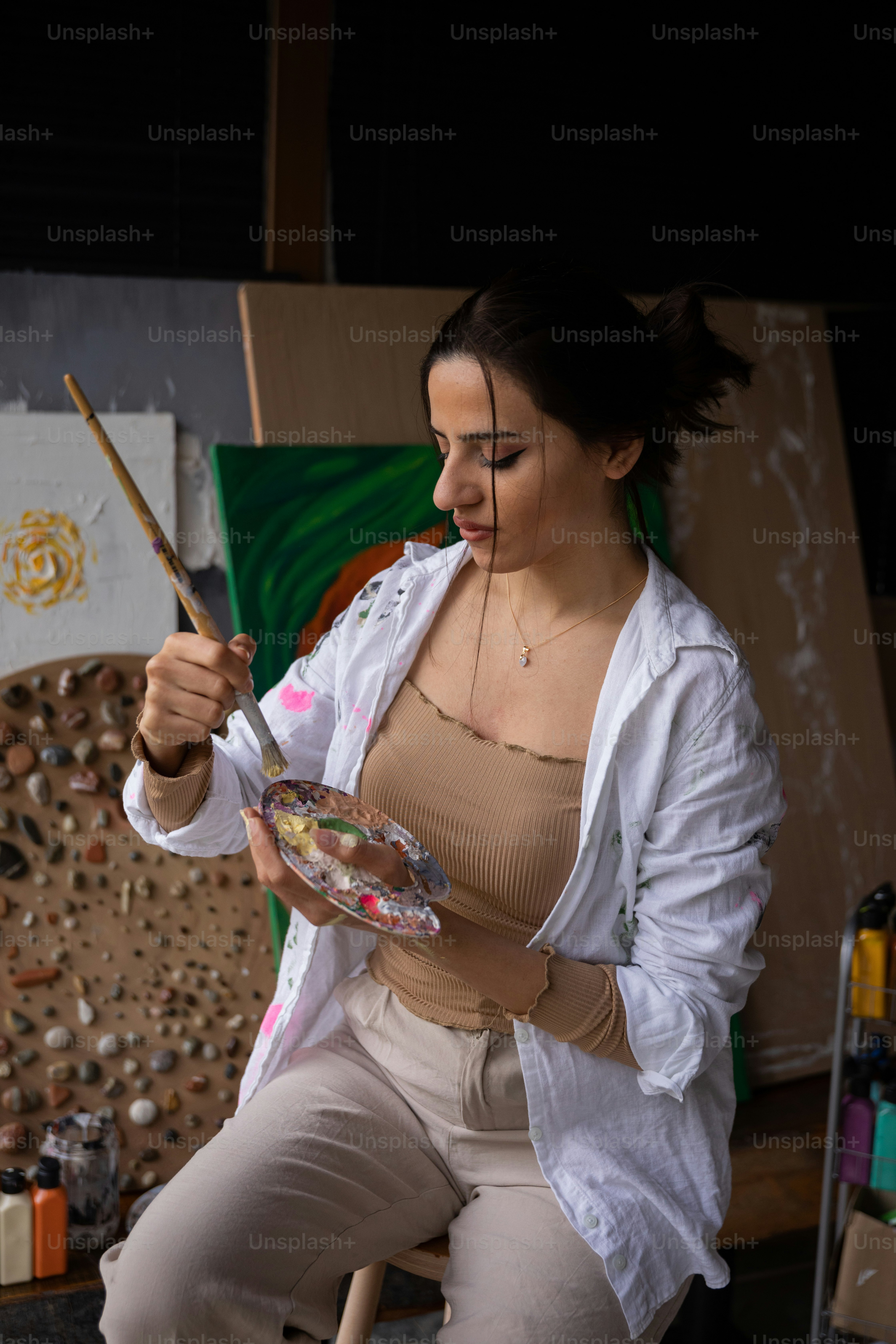a woman sitting in a chair holding a paintbrush