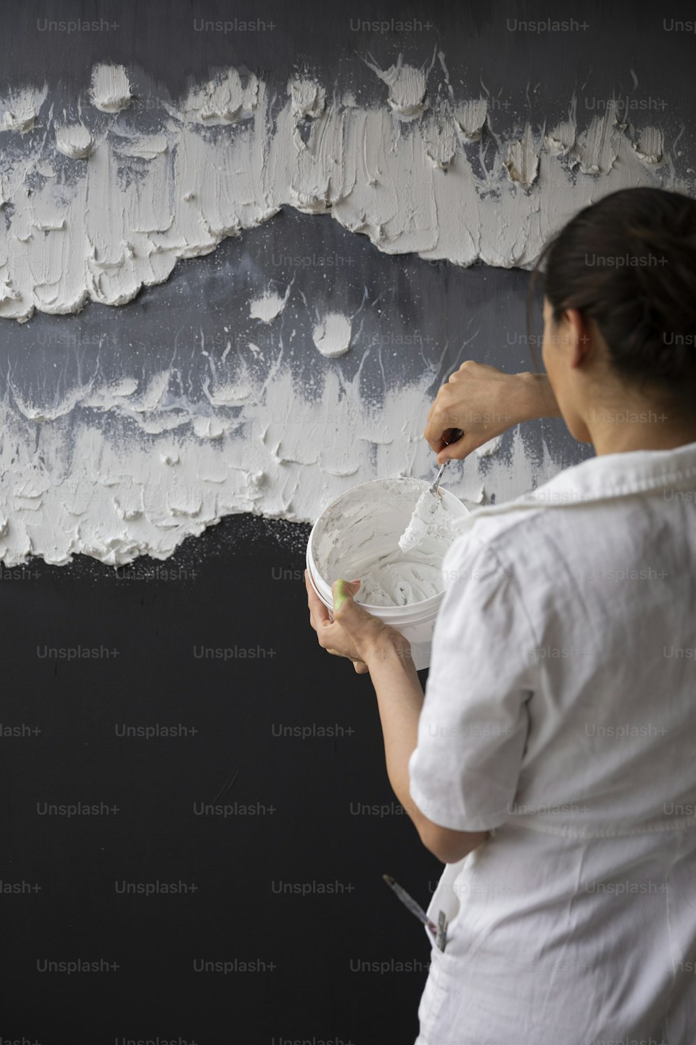 Una mujer pintando una pared con pintura blanca