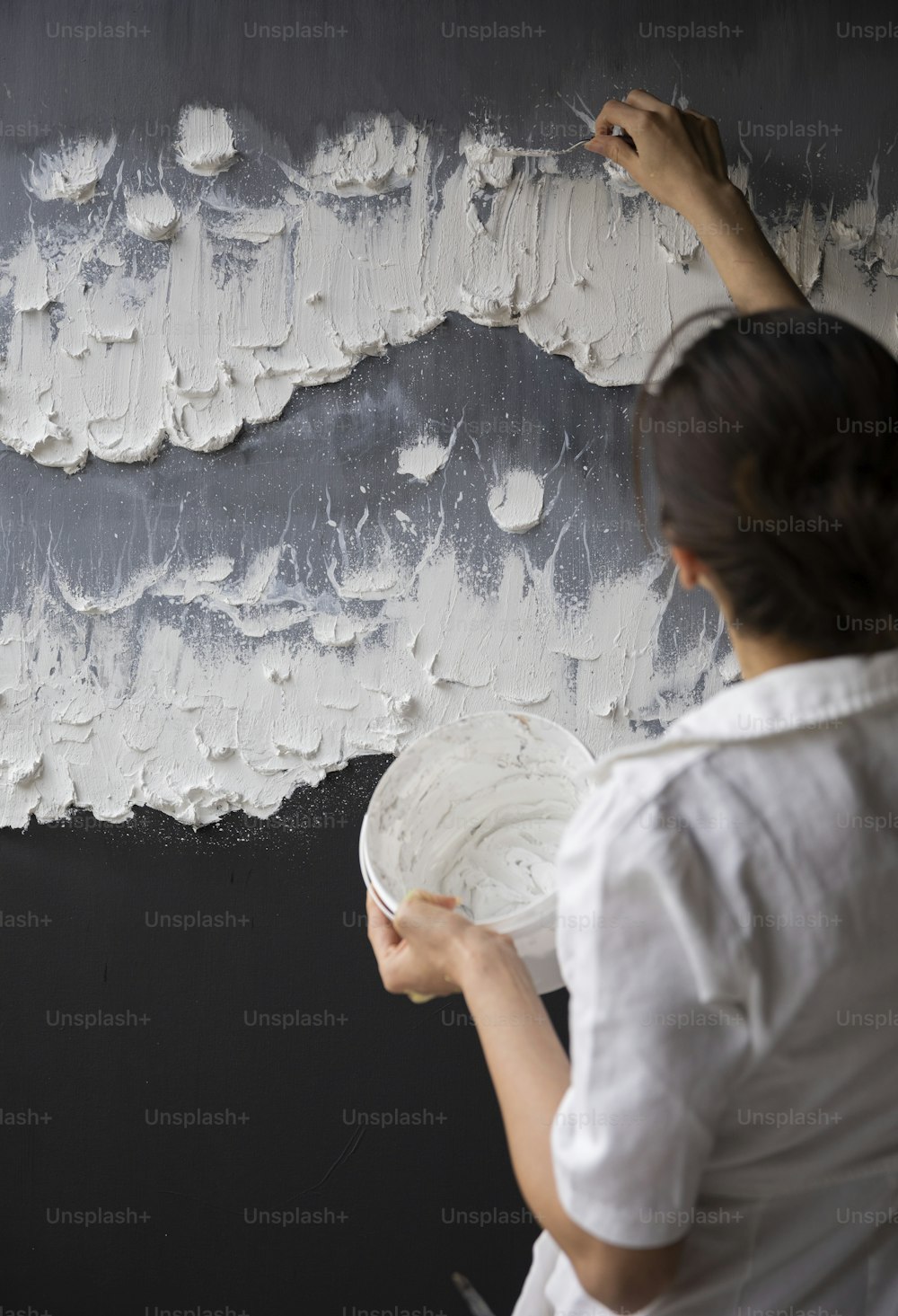 Eine Frau, die eine Wand mit weißer Farbe bemalt