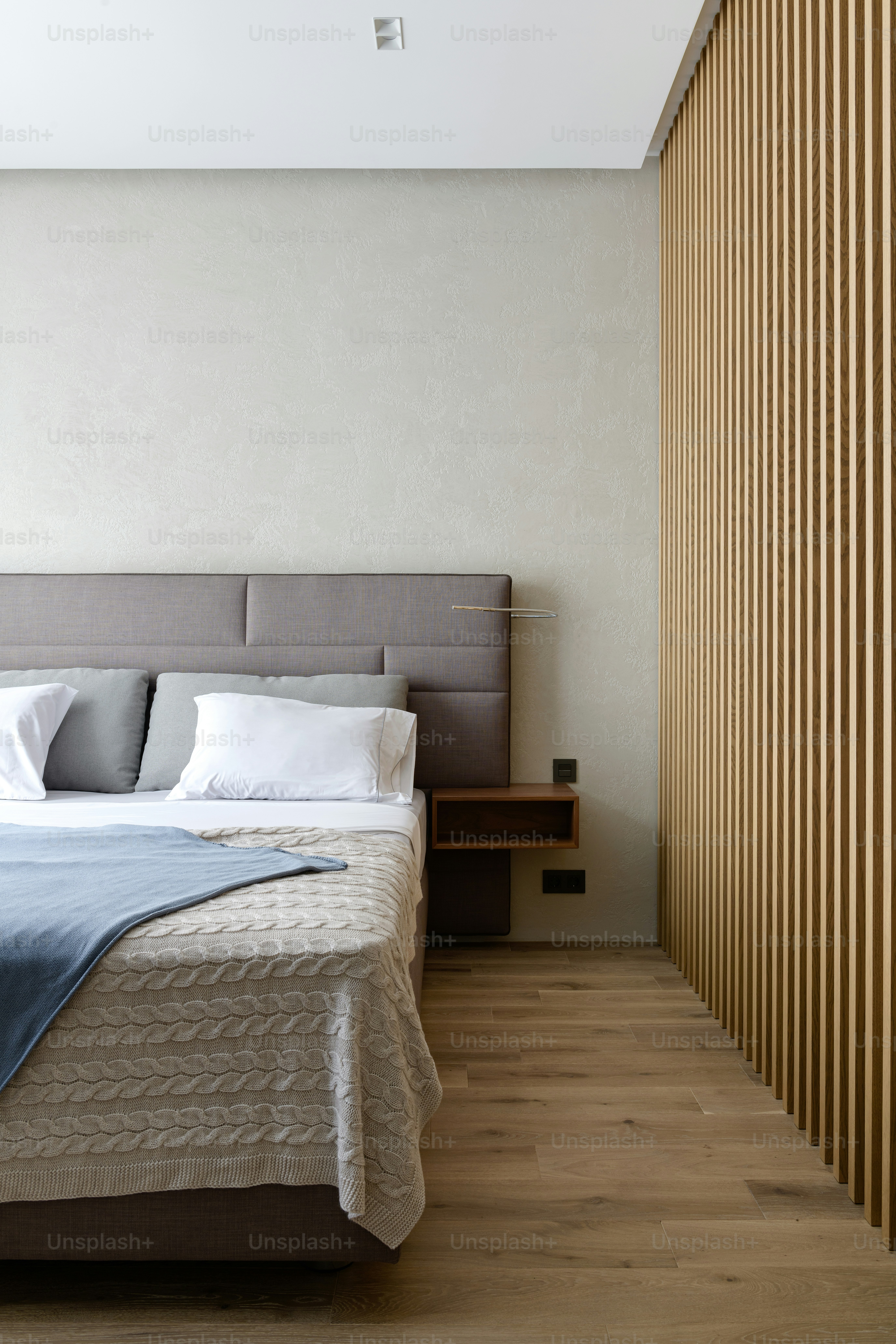 a bedroom with a large bed and a wooden slatted wall
