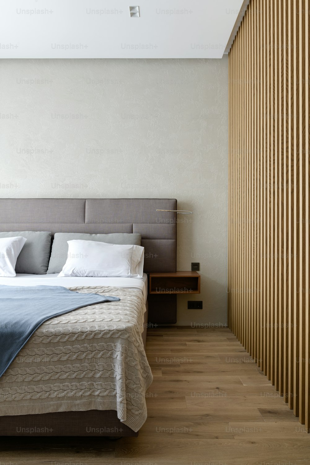 a bedroom with a large bed and a wooden slatted wall