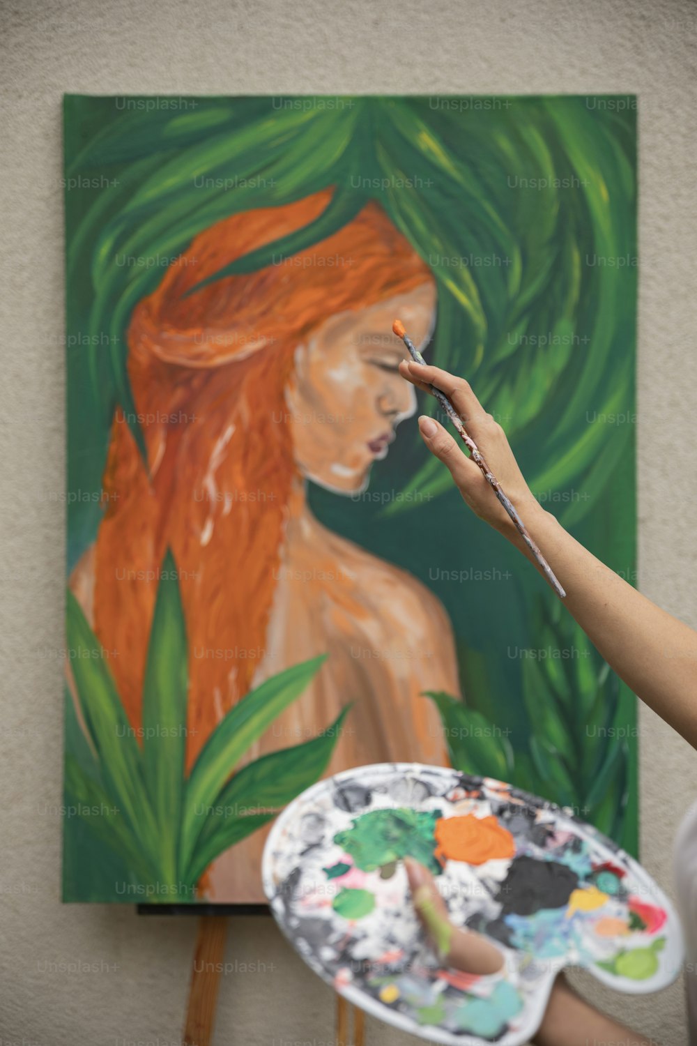 a woman holding a paintbrush in front of a painting