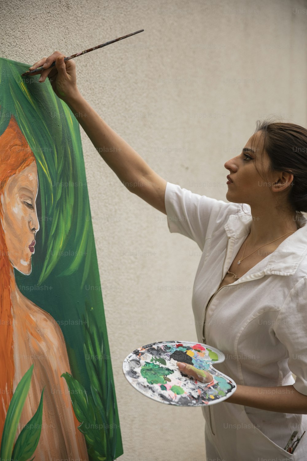 a woman is painting a picture on a canvas