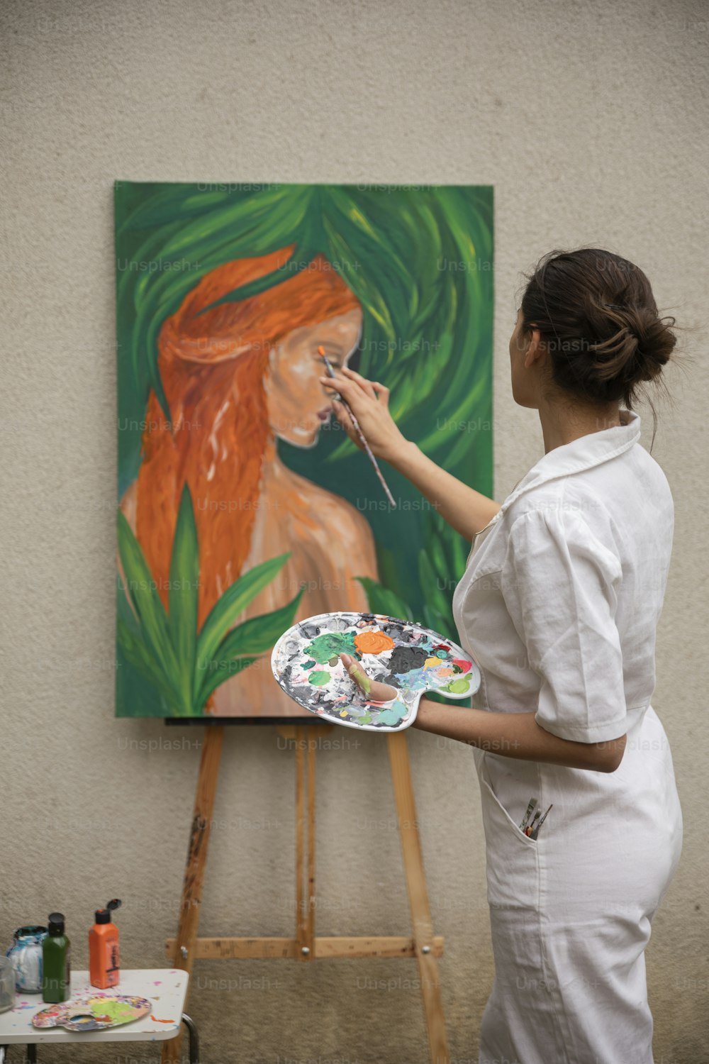 女性がイーゼルに絵を描いている