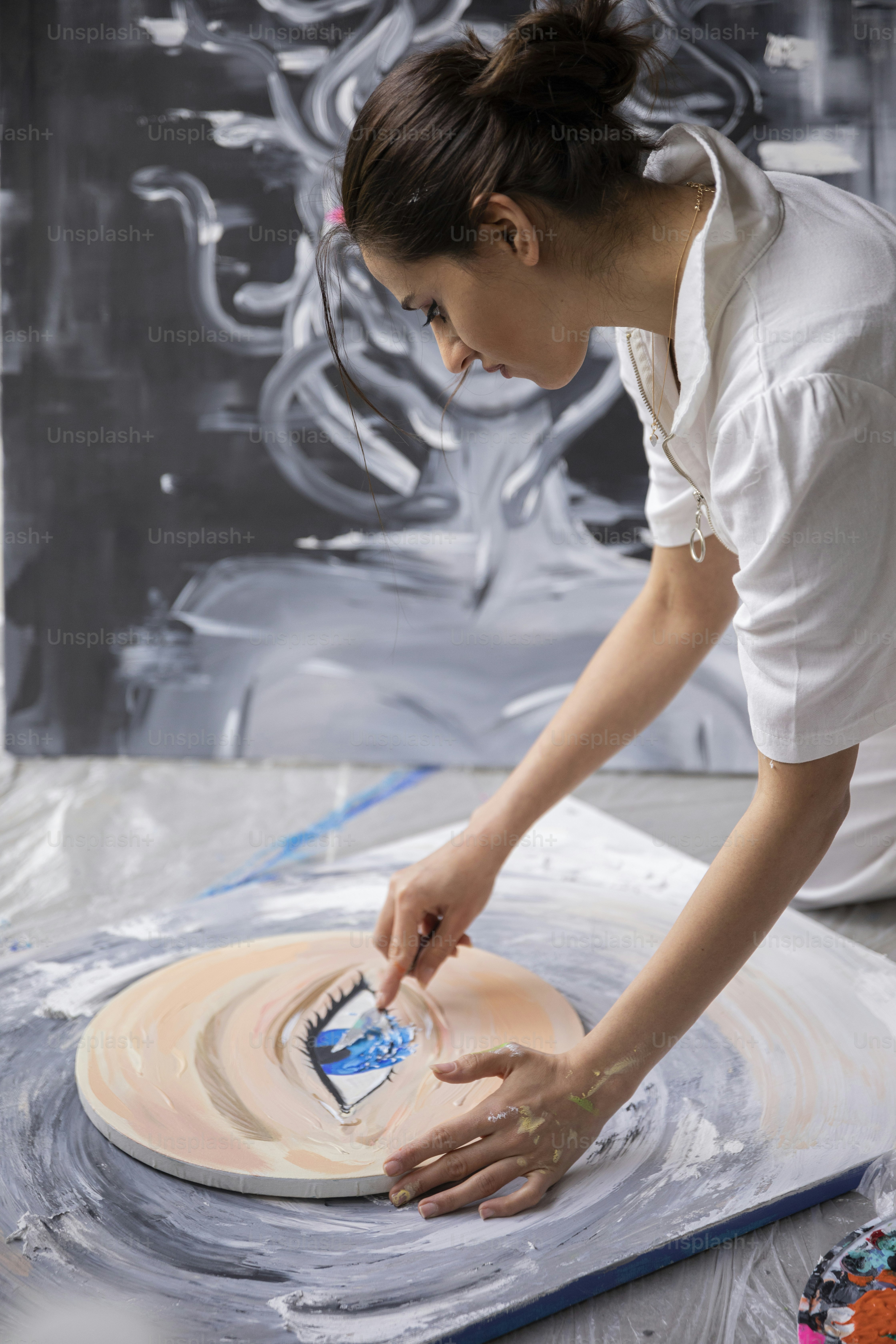 Une femme en chemise blanche travaille sur une œuvre d’art