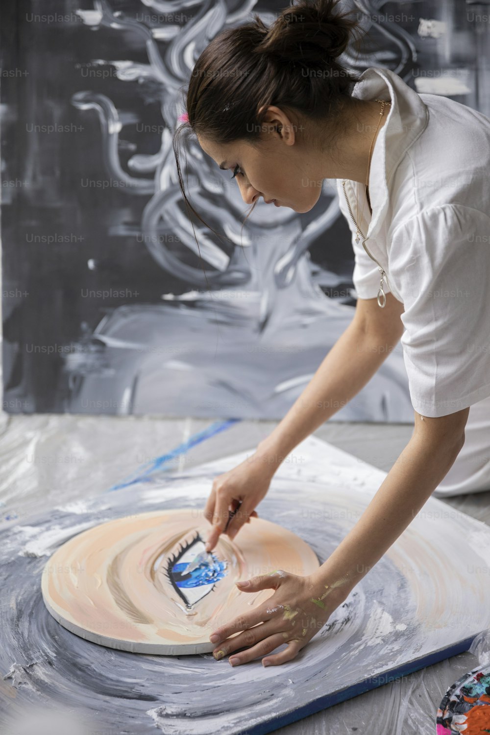 uma mulher em uma camisa branca está trabalhando em uma obra de arte
