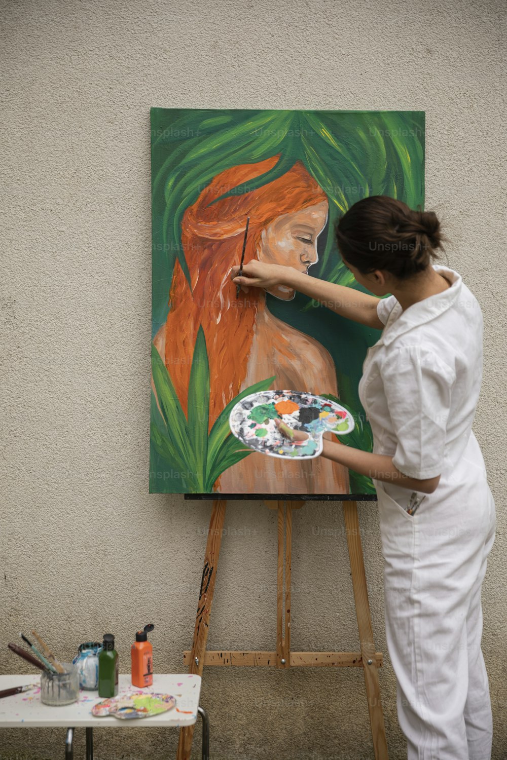 a woman is painting a picture on a easel