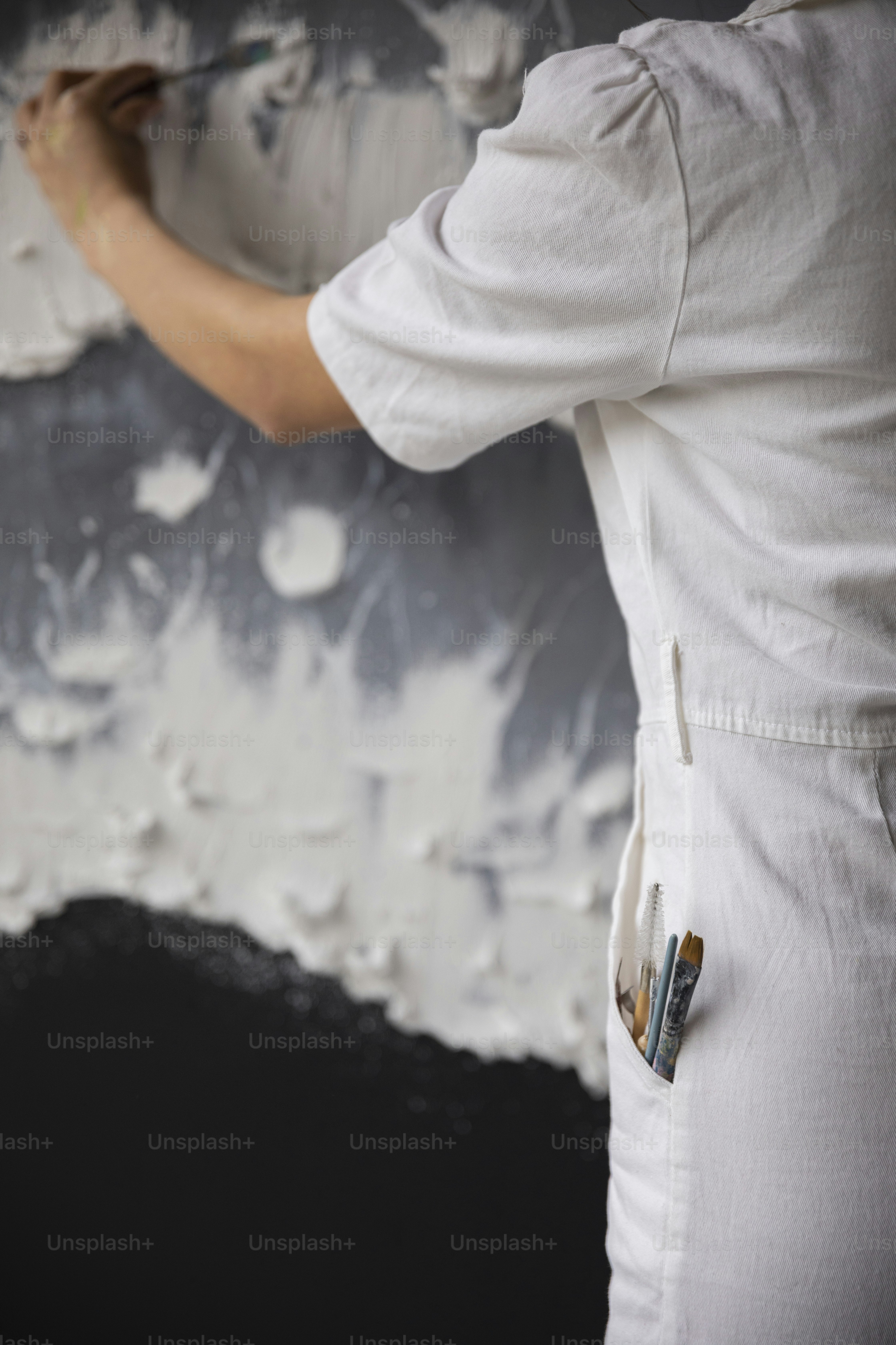 a woman is painting a wall with white paint