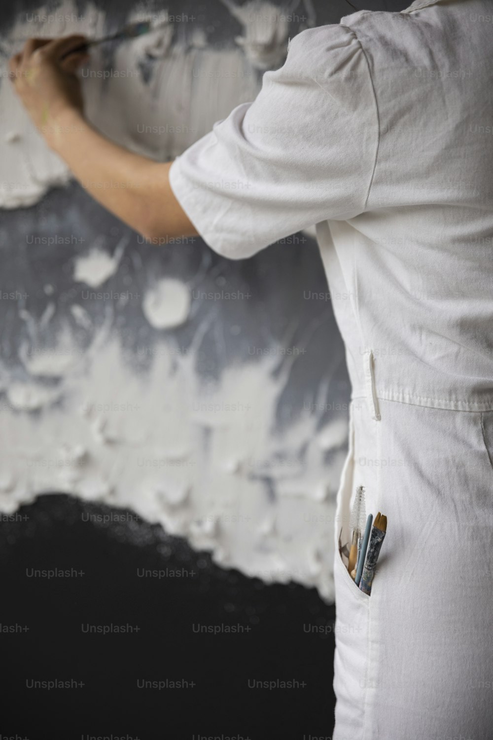 Eine Frau streicht eine Wand mit weißer Farbe