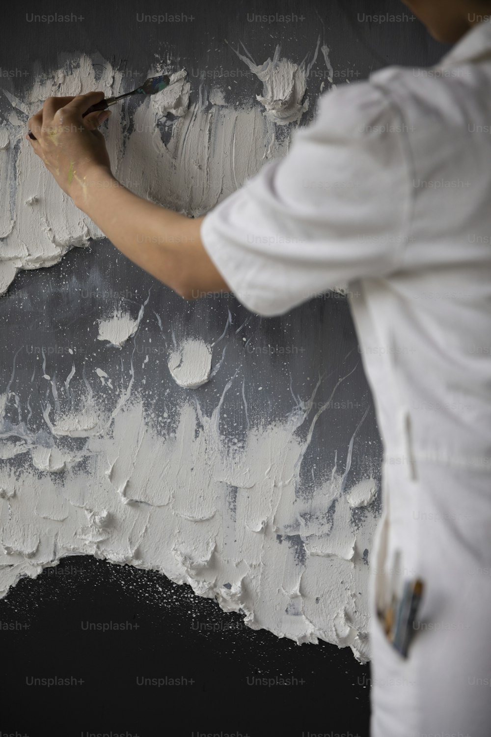 Ein Mann streicht eine Wand mit weißer Farbe