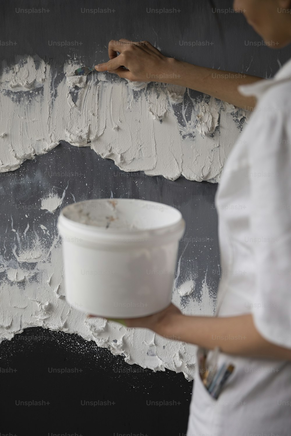 Eine Frau streicht eine Wand mit weißer Farbe