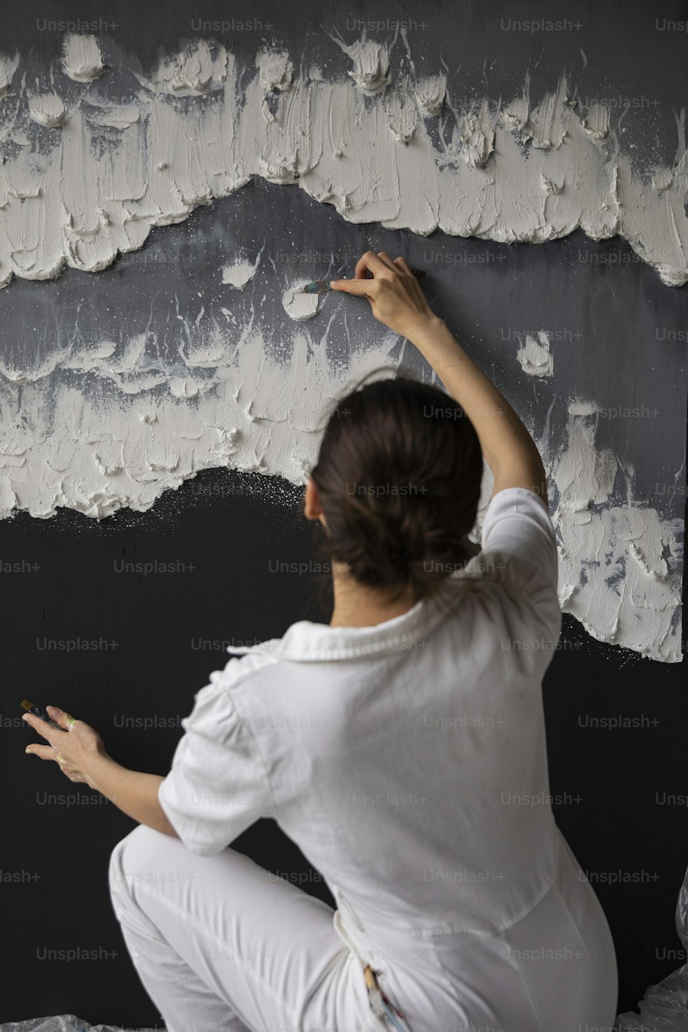 흰색 페인트로 벽을 칠하는 여자