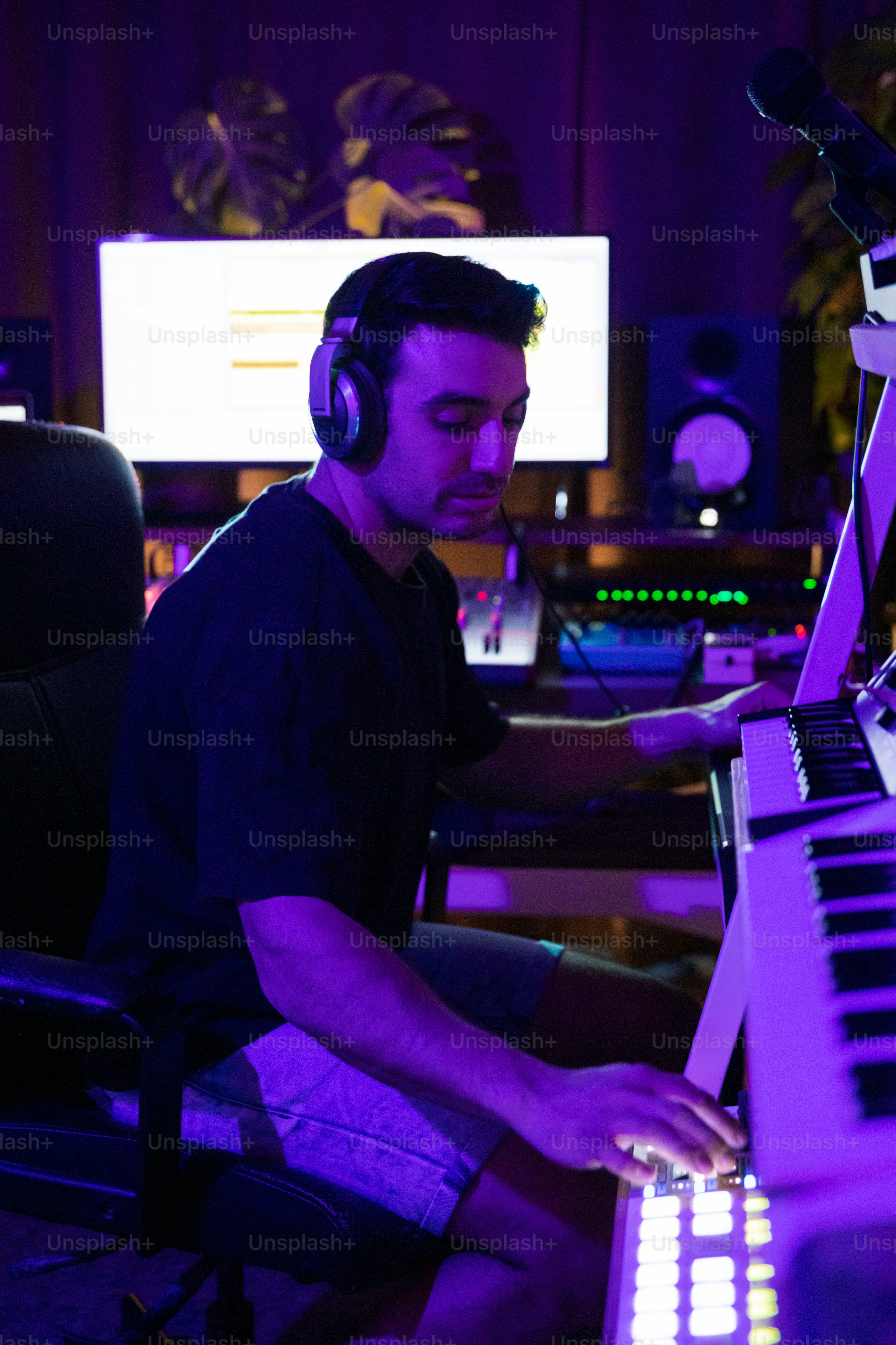 um homem sentado na frente de um teclado com fones de ouvido ligados