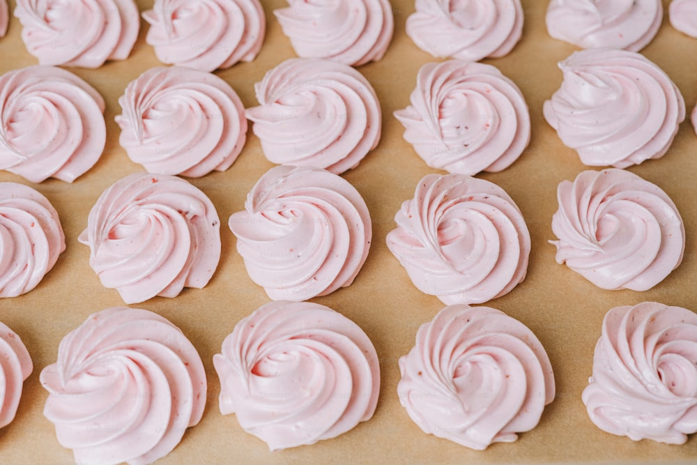 a tray of pink frosted cupcakes sitting on top of a table