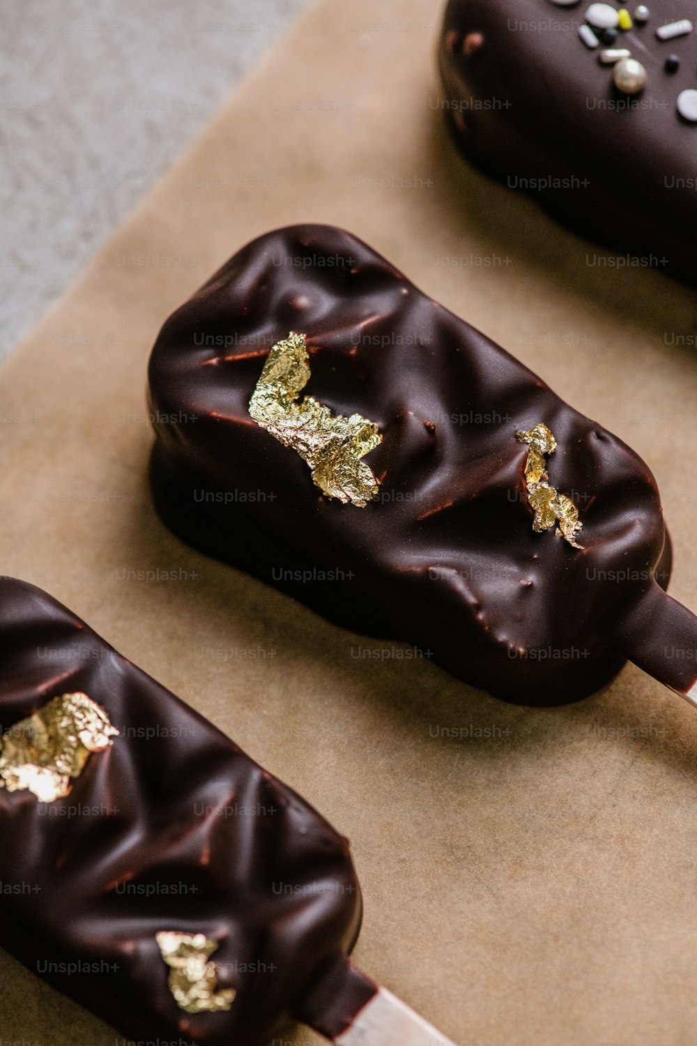 Tres donas cubiertas de chocolate en un pedazo de papel