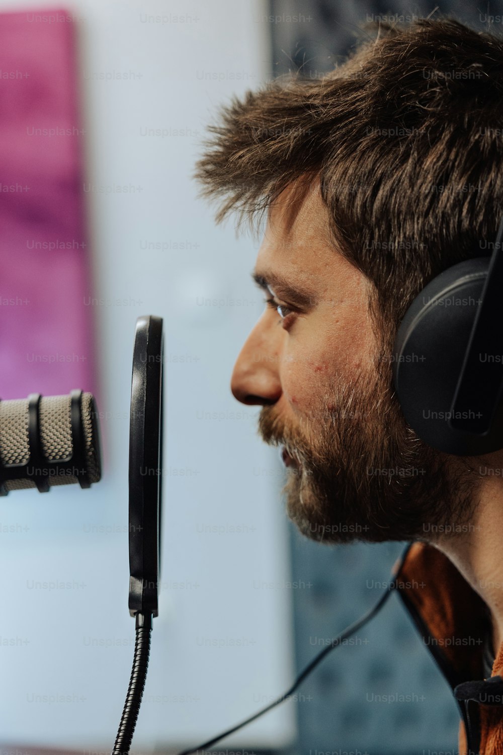 Un hombre con barba con auriculares frente a un micrófono