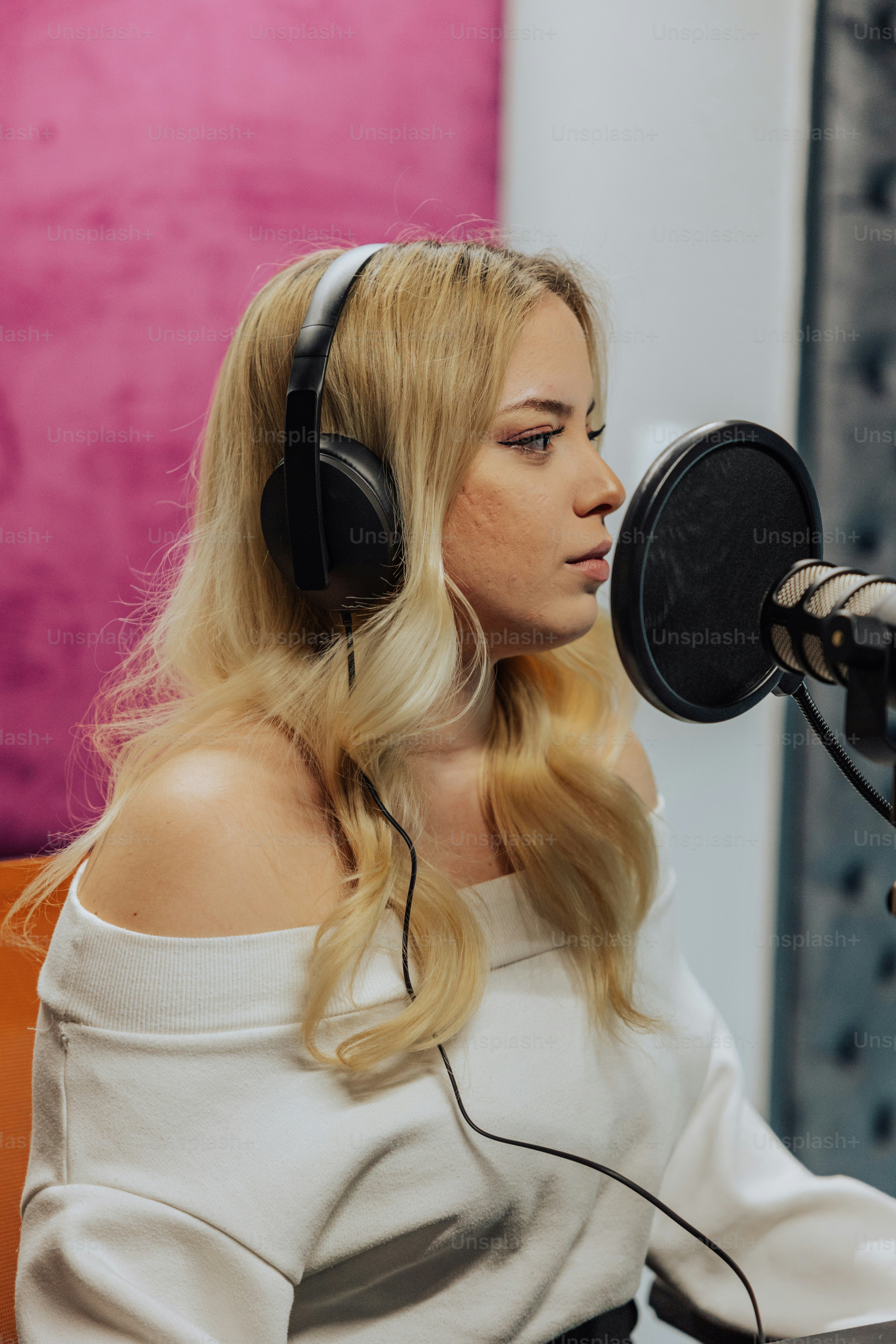 a woman sitting in front of a microphone wearing headphones