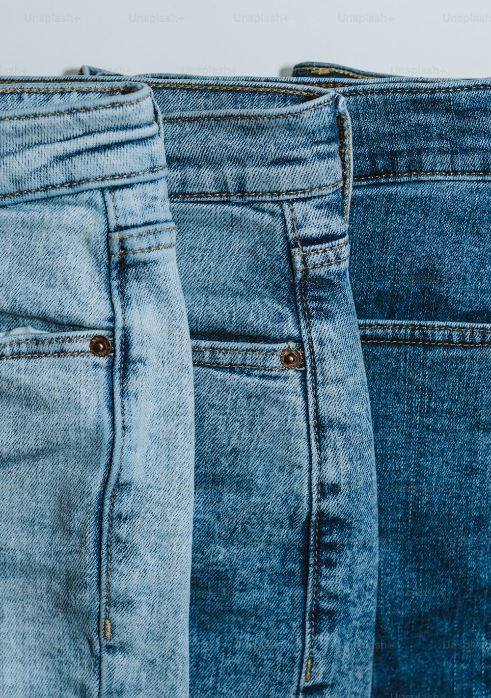 three pairs of jeans are lined up in a row