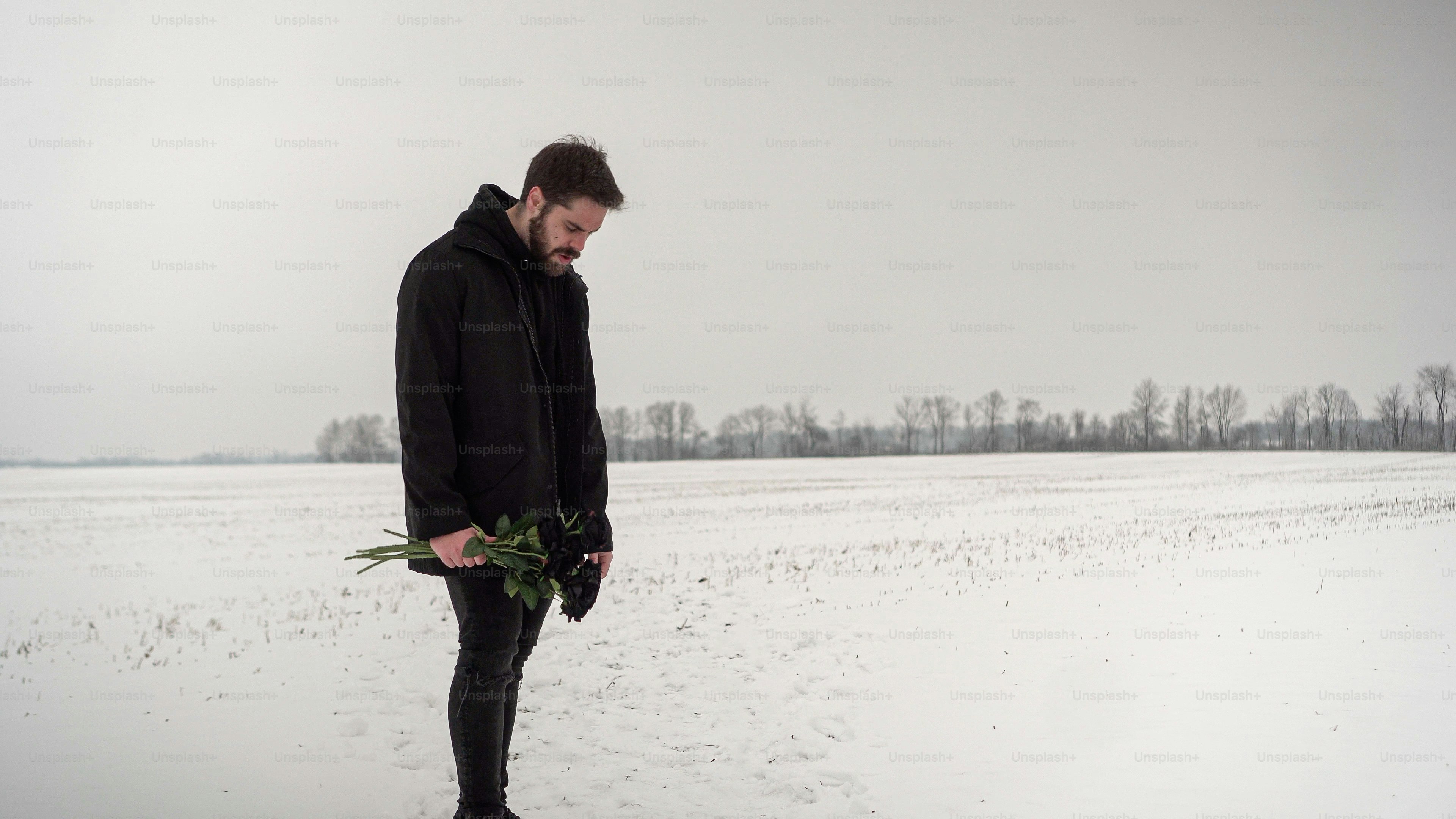 A winter music video shoot featuring a male model. Winter landscape in an open field, with black roses.