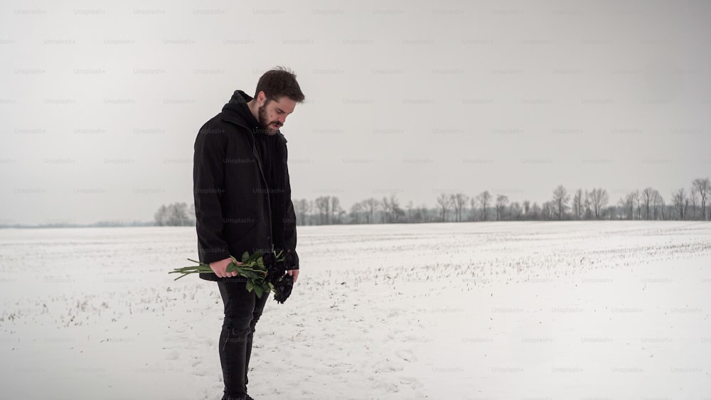 a man standing in the snow holding a bouquet of flowers