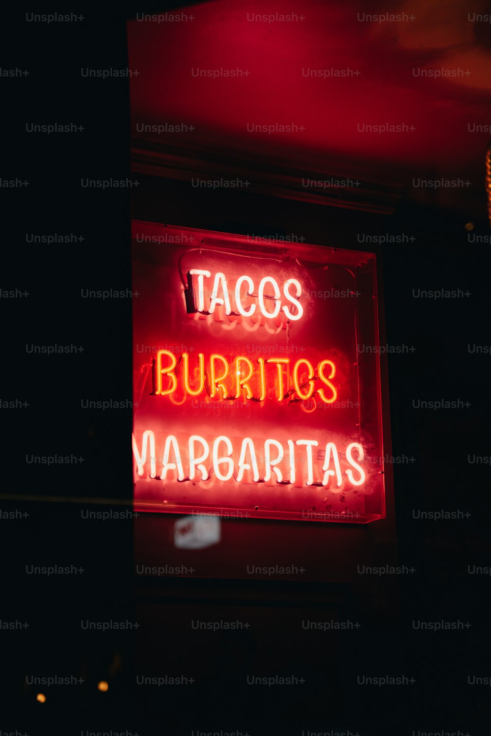 Un letrero de neón que dice tacos burritos margaritas