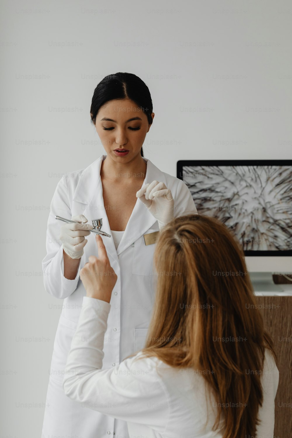 a woman in a white lab coat is cutting another woman's hair