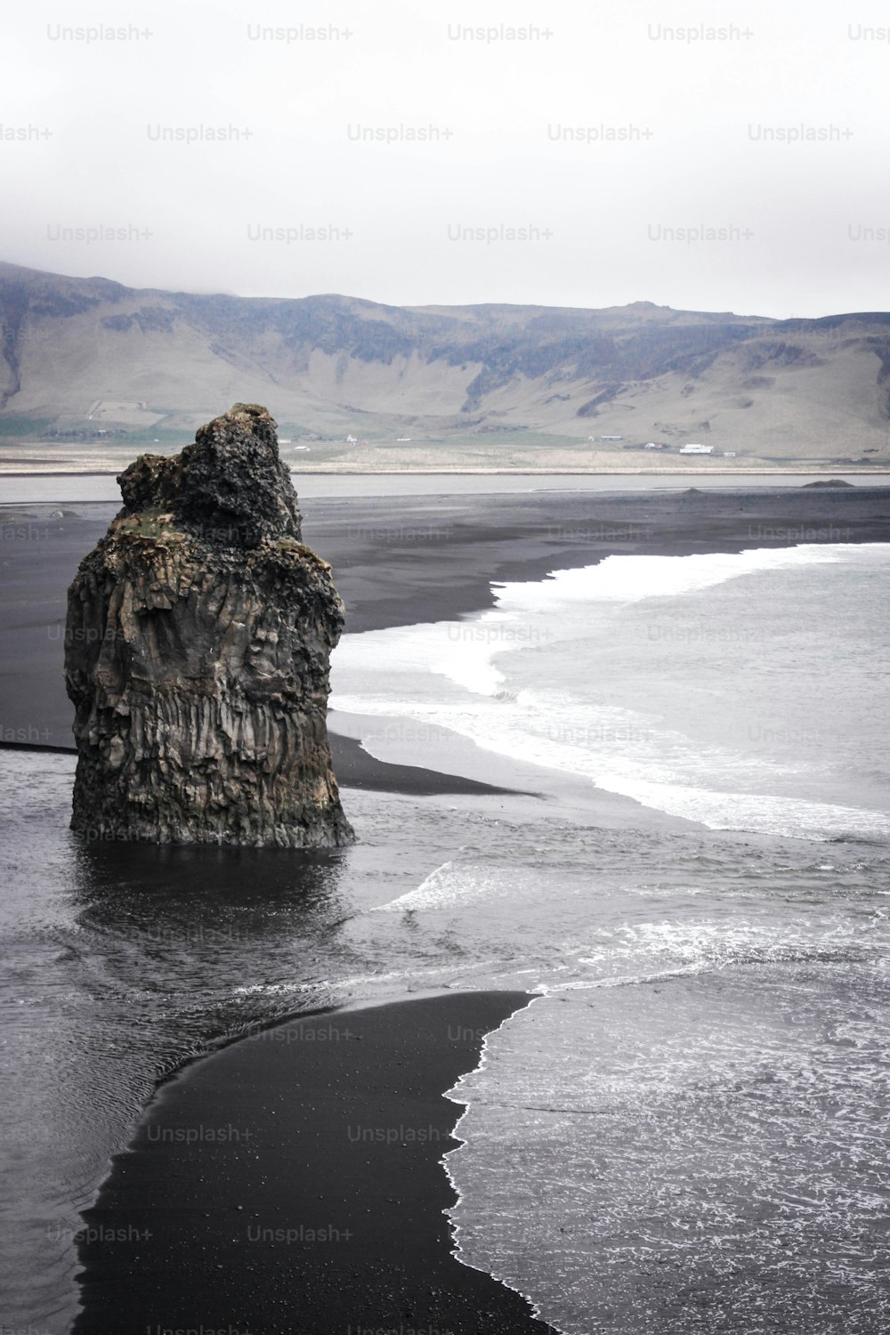 Ein großer Felsen, der an einem Strand aus dem Wasser ragt