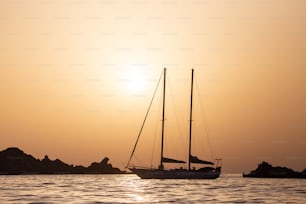 a sailboat in the ocean at sunset