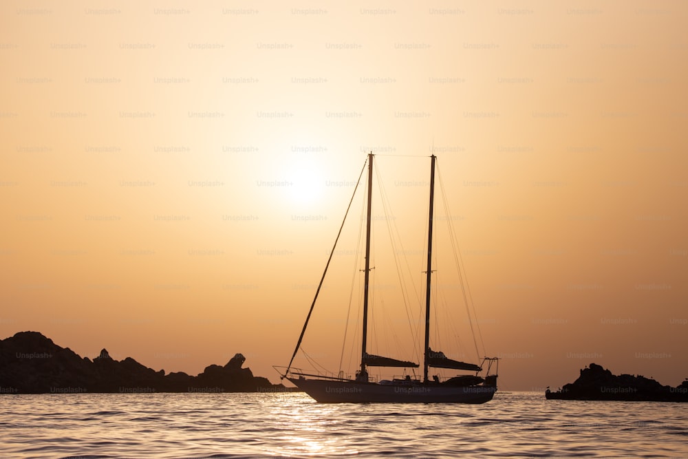 a sailboat in the ocean at sunset