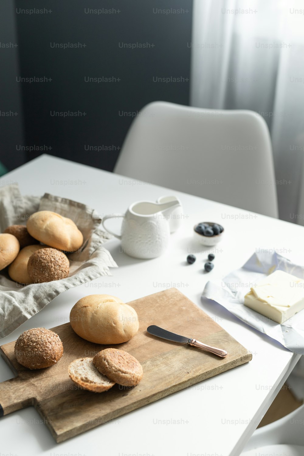 uma mesa com uma tábua de corte com pão sobre ela