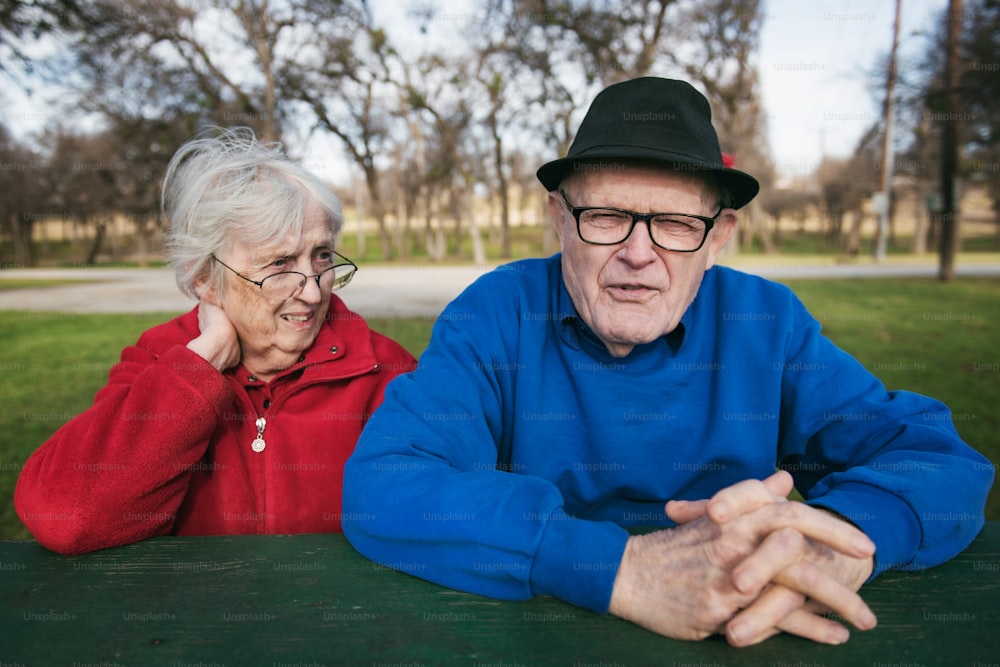 um homem e uma mulher sentados em uma mesa em um parque