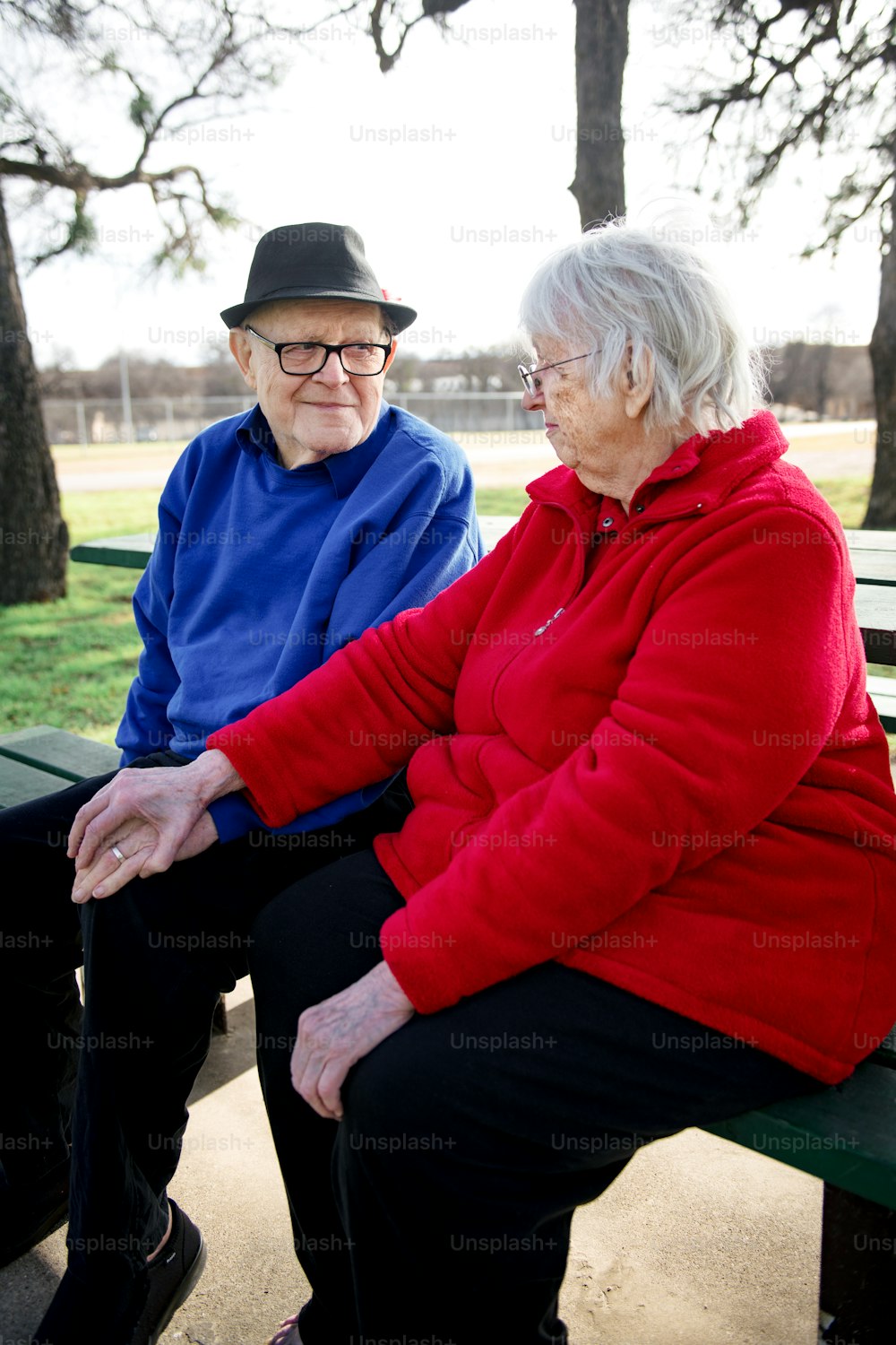 an older couple sitting on a bench in a park