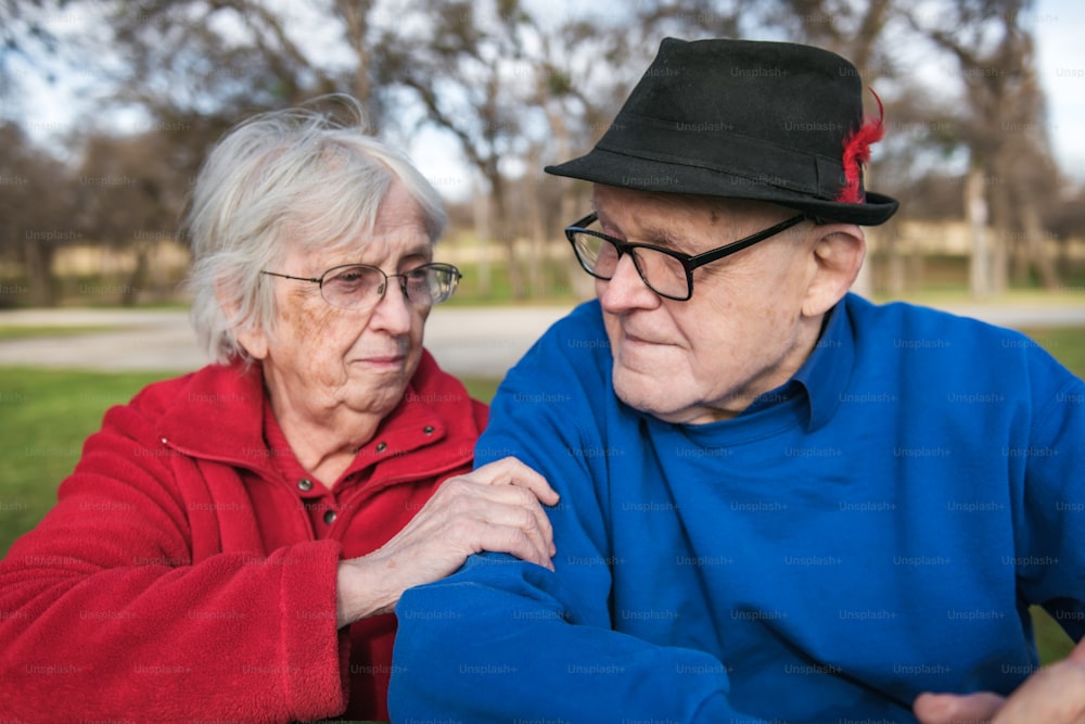 an older couple sitting on a bench in a park