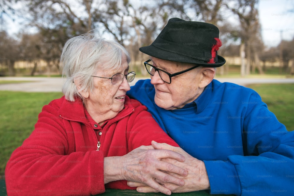 an older couple sitting on a bench in a park